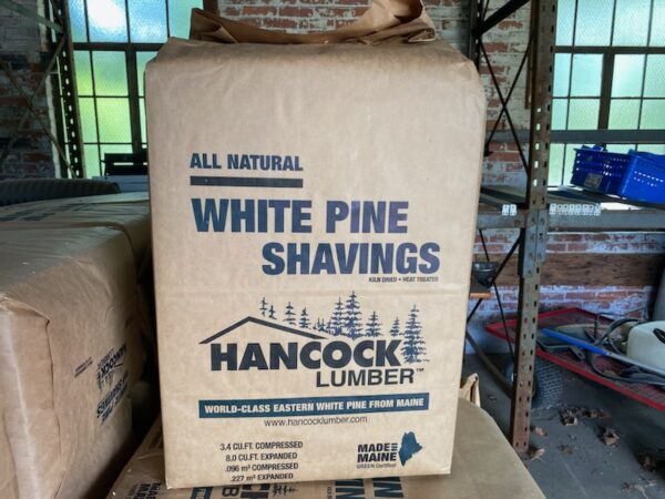 A box of white pine shavings sitting on top of boxes.